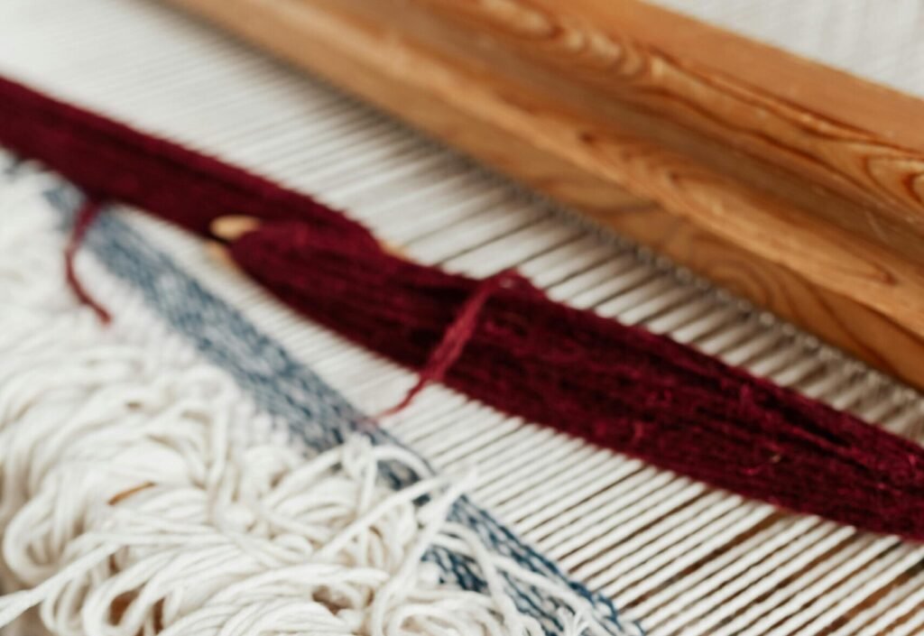 pexels-photo-4219610-4219610 Close-up of a handwoven textile on a loom in an artisan workshop, showcasing traditional craftsmanship.