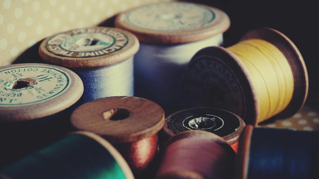 A close-up of vintage wooden spools displaying colorful sewing threads for crafting and tailoring.