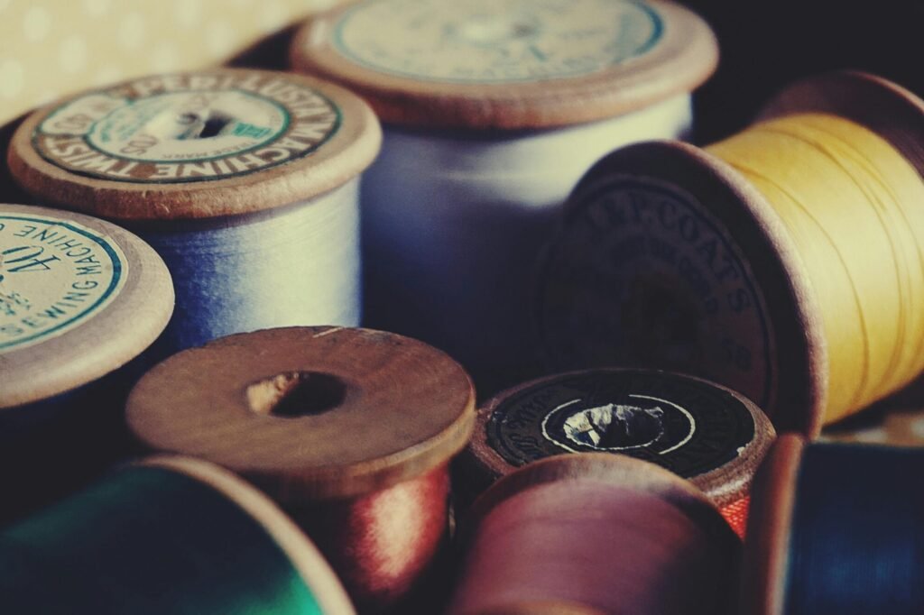 A close-up of vintage wooden spools displaying colorful sewing threads for crafting and tailoring.