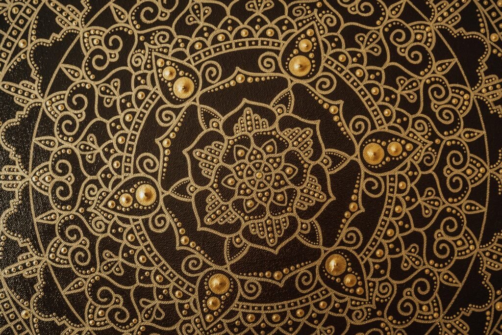 Close-up of an intricate gold mandala pattern on a dark canvas, showcasing detailed artistry.
