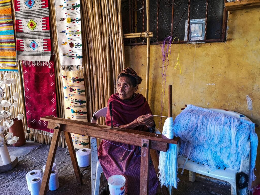 Elderly woman crafting handmade rugs in Teotitlan del Valle, showcasing traditional textile art.