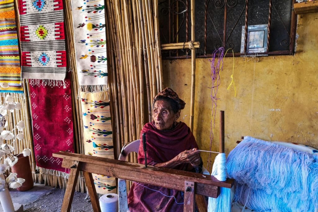 Elderly woman crafting handmade rugs in Teotitlan del Valle, showcasing traditional textile art.